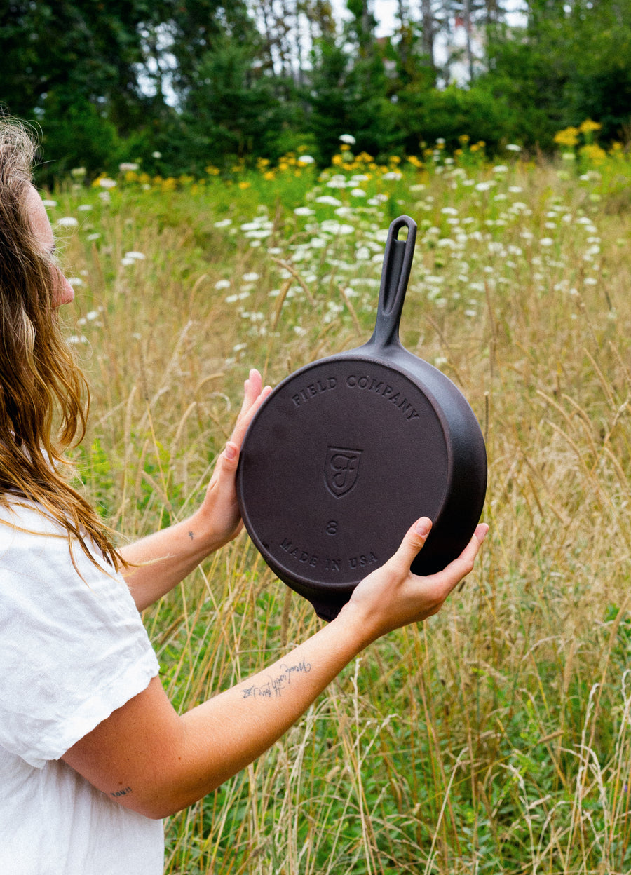 Woman in a meadow holding the No.8 Cast Iron Skillet with its Field Company and Made in USA stamps facing out