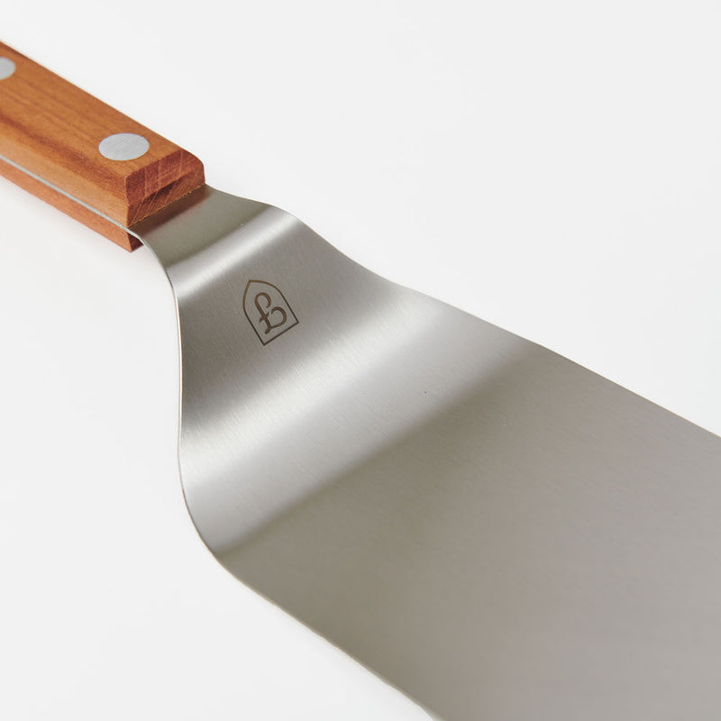 Close-up of the Field Griddle Turner's offset stainless blade and riveted cherry wood handle