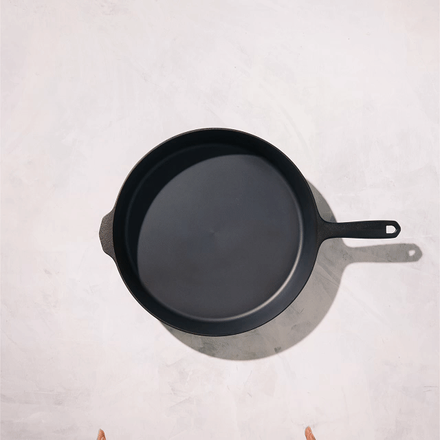 Overhead view of the No.12 Field Cast Iron Skillet on a plaster surface, helper handle opposite the main handle