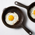 Fried eggs cooking in two No.4 Field Cast Iron Skillets, overhead view thumbnail