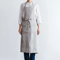 Model wearing the Field Company gray linen full length apron tied at the waist over a white shirt thumbnail