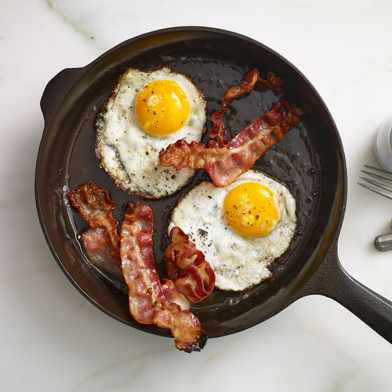 Fried eggs and crispy bacon cooking in the No.8 Field Cast Iron Skillet, overhead view