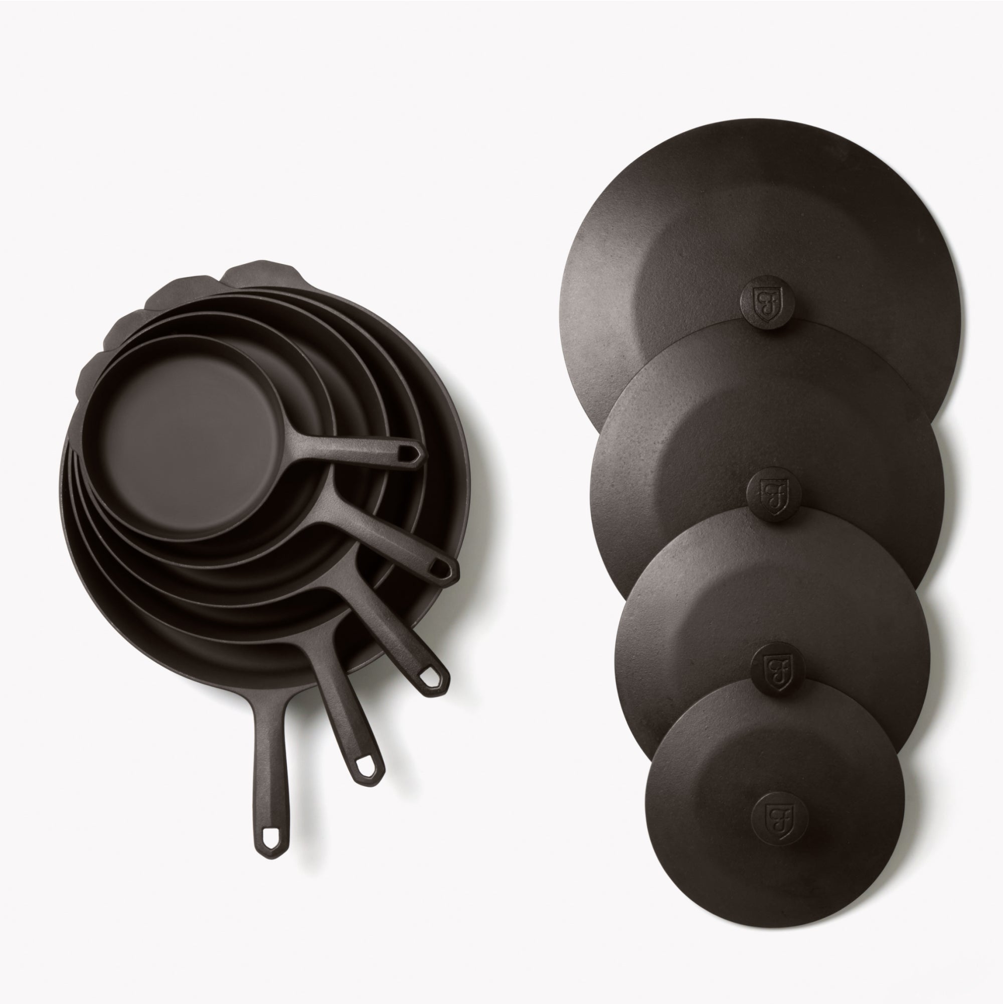 Overhead of the Field 9-Piece Set: nested skillets and griddle beside four graduated cast iron lids