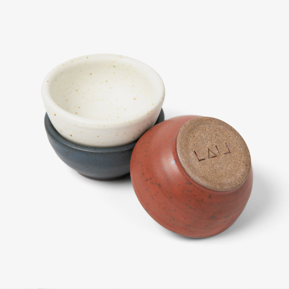 Field Company Tiny Ceramic Bowls in bone, navy, and terracotta, one turned to show its stamped clay base