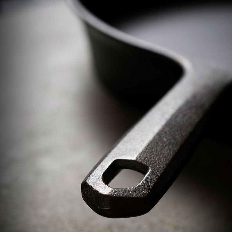 Close-up of the Field Skillet handle and hanging hole on a dark background