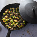 Crispy roasted brussels sprouts in the Field Skillet, its cast iron lid resting ajar thumbnail