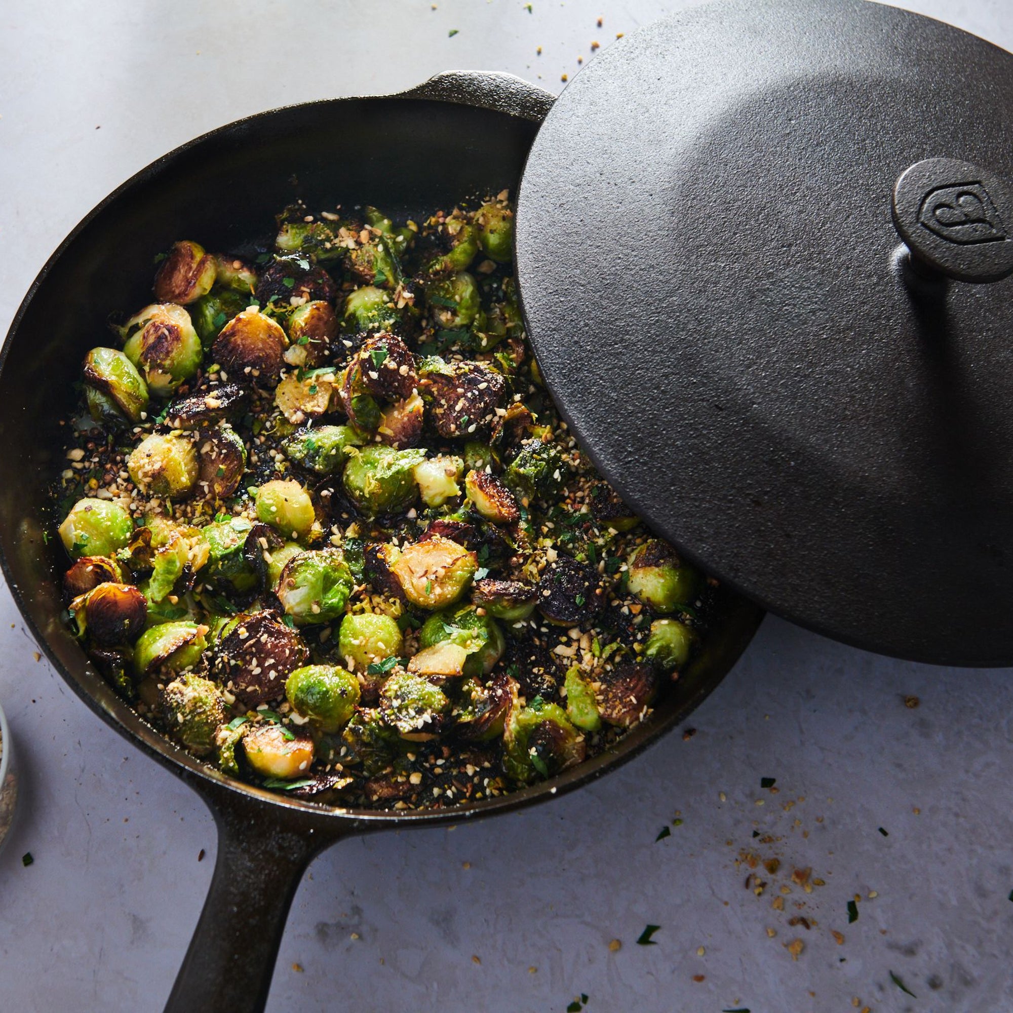Crispy roasted brussels sprouts in the Field Skillet, its cast iron lid resting ajar