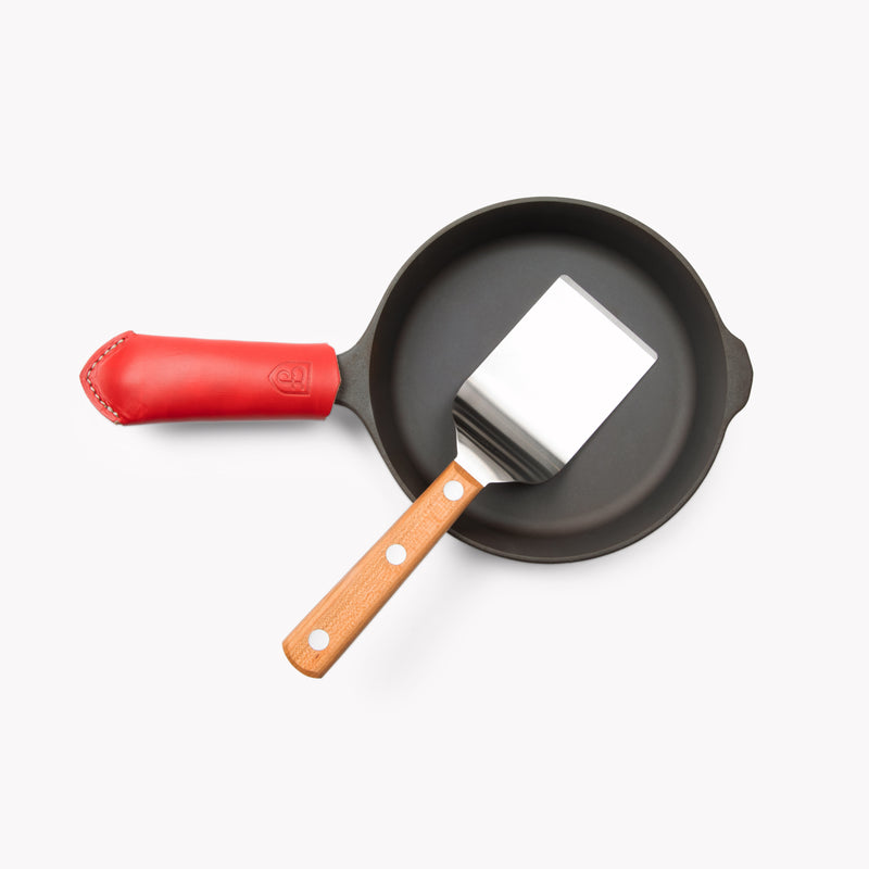 Overhead of The Minis: mini turner resting inside a small Field Skillet with red leather handle cover