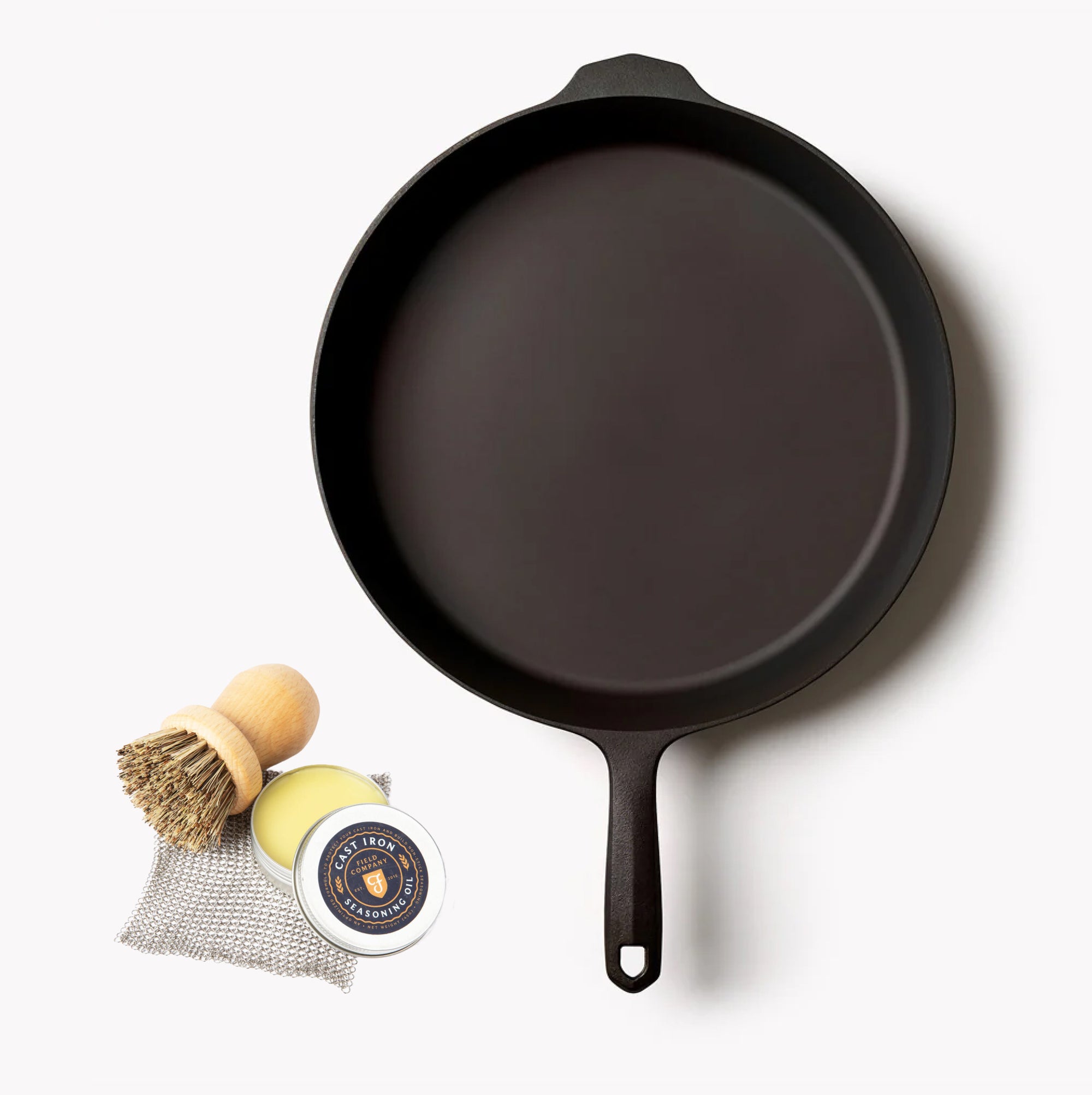 Overhead of the No.12 Field Cast Iron Skillet with scrub brush, seasoning oil, and chain mail from the Starter Set