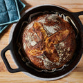 Golden sourdough loaf on parchment inside the No.10 Field Dutch Oven, overhead on a wooden counter thumbnail