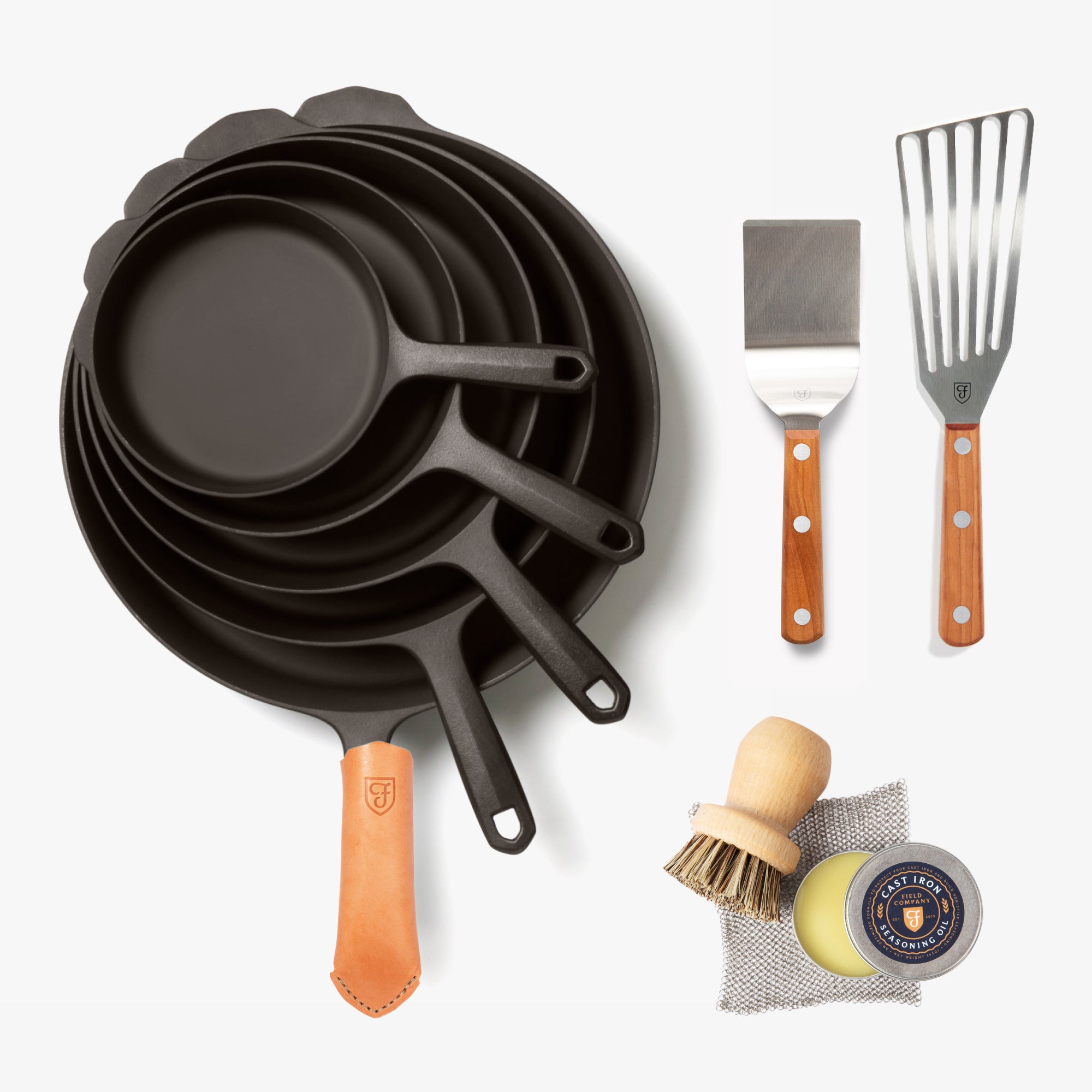 Overhead of the Hosting Set: nested Field Skillets with leather handle cover, two turners, and care tools