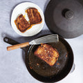 Grilled cheese frying in the No.6 Field Cast Iron Skillet, slotted turner and plated halves alongside thumbnail