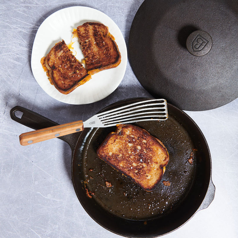 Grilled cheese frying in the No.6 Field Cast Iron Skillet, slotted turner and plated halves alongside