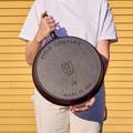Person holding the No.12 Field Cast Iron Skillet upside down to show its stamped underside, outdoors in sunlight thumbnail
