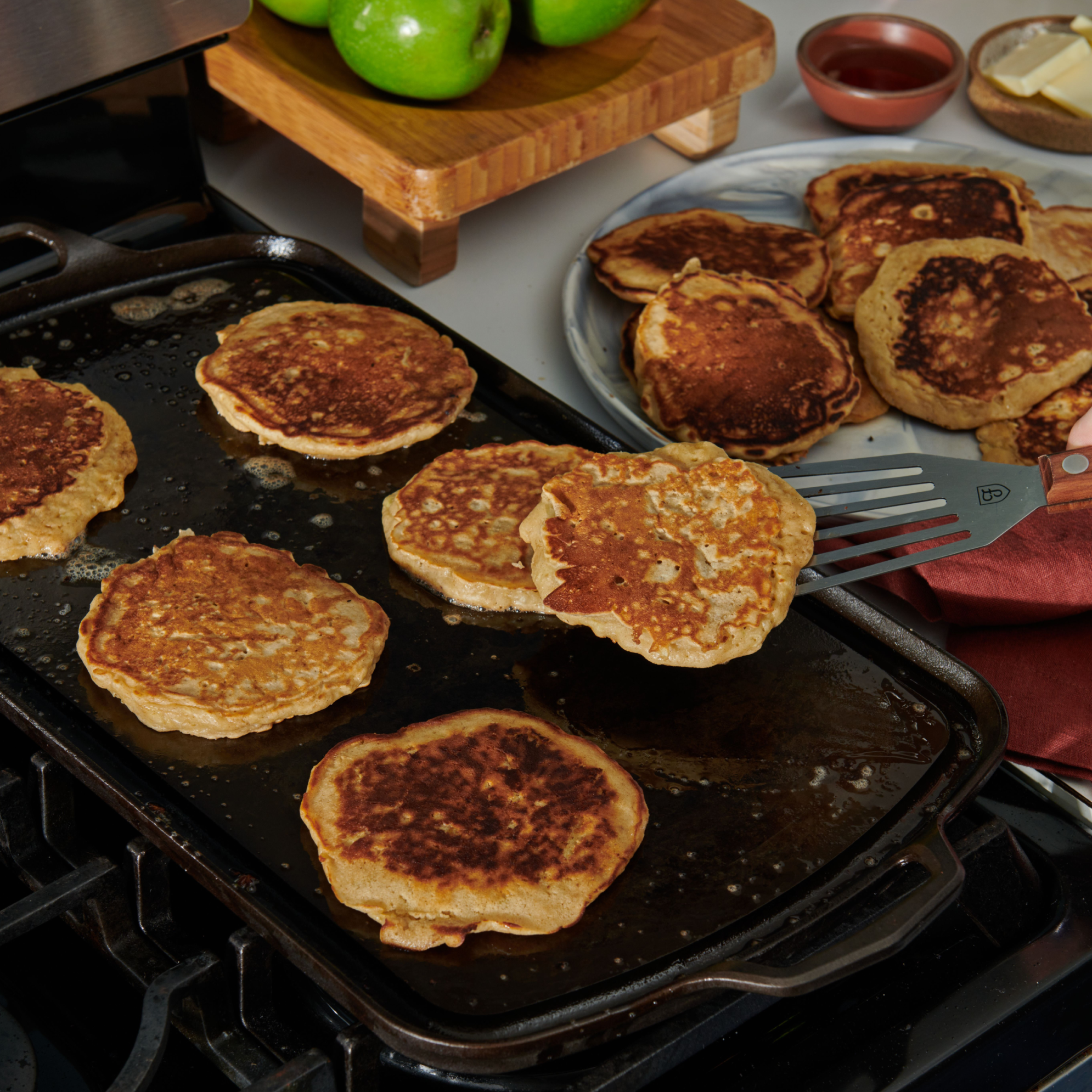 Golden pancakes cooking on the Field Long Cast Iron Griddle on the stovetop