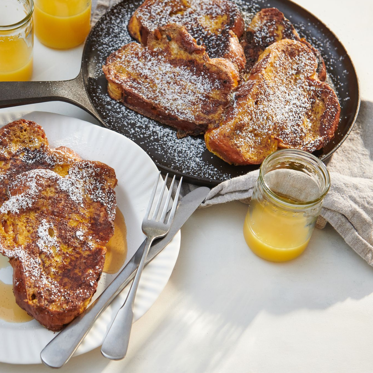 French toast slices on the No.9 Round Field Griddle with plates and orange juice alongside