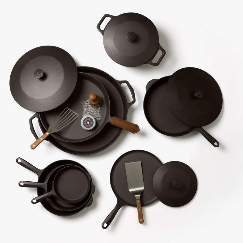 Overhead view of the 12-Piece Field Cast Iron Set: skillets, Dutch ovens, griddles, lids, and wood-handled turners