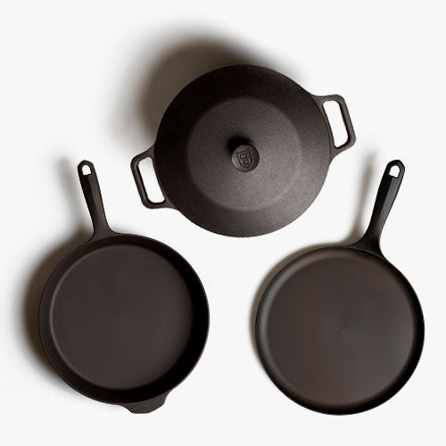 Overhead of the Field 4-Piece Set: lidded Dutch oven, skillet, and round griddle on white background