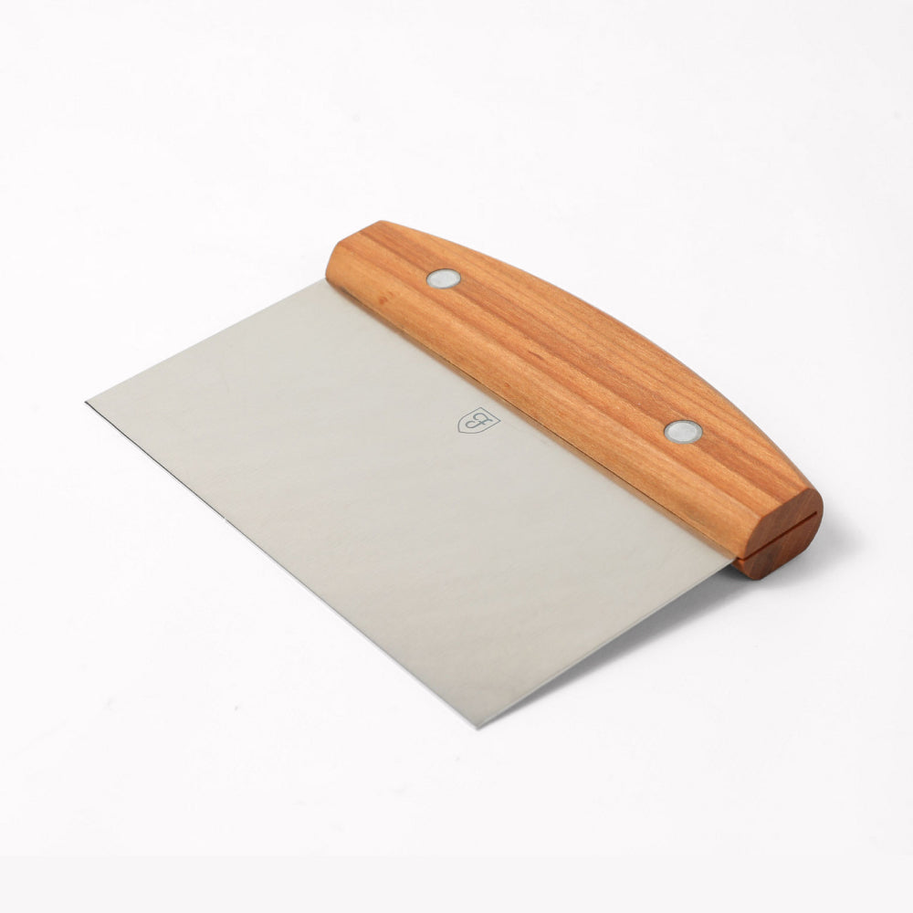 Angled view of the Field Bench Scraper with cherry wood handle and stainless steel blade