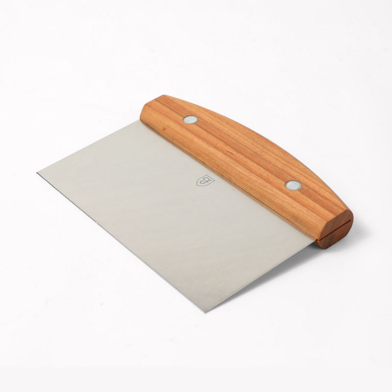 Angled view of the Field Bench Scraper with cherry wood handle and stainless steel blade