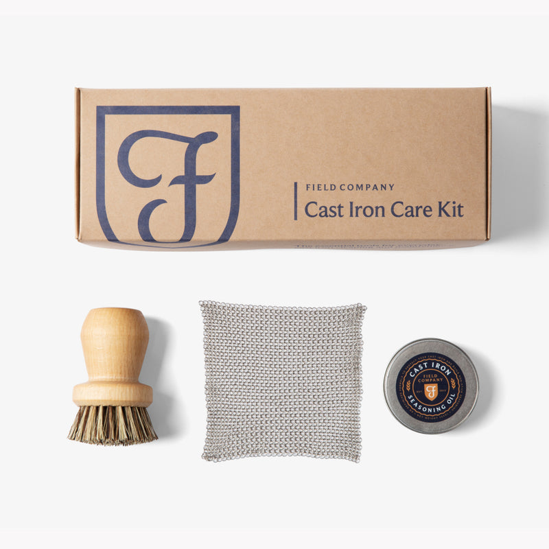 Field Company Cast Iron Care Kit box above the wood scrub brush, chain mail scrubber, and seasoning oil tin