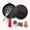 Overhead of the Chef's Starter Set No.8: Field Skillet with lid, slotted turner, red handle cover, and care tools thumbnail