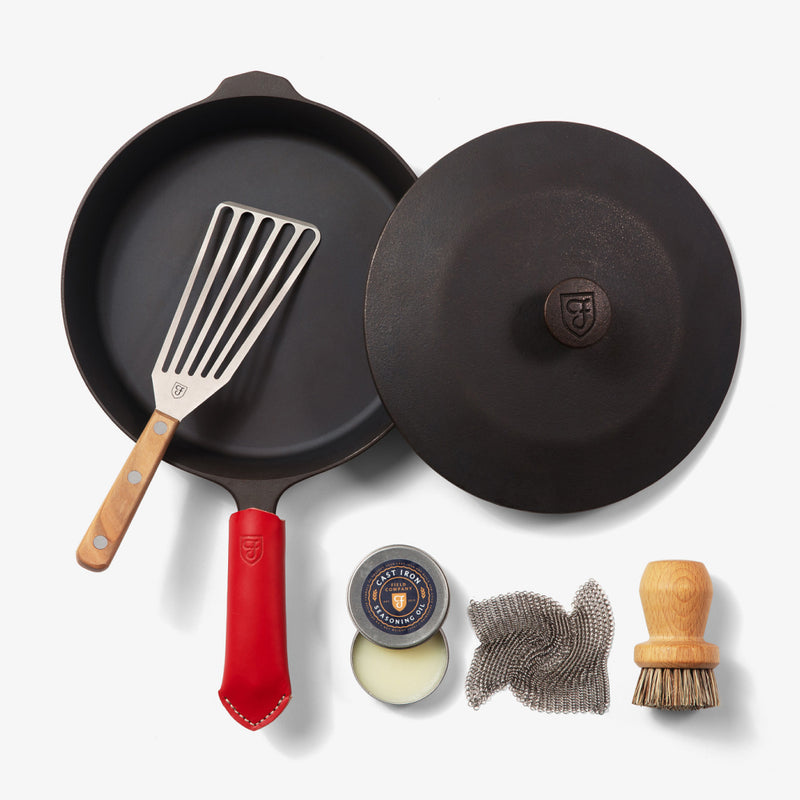 Overhead of the Chef's Starter Set No.8: Field Skillet with lid, slotted turner, red handle cover, and care tools
