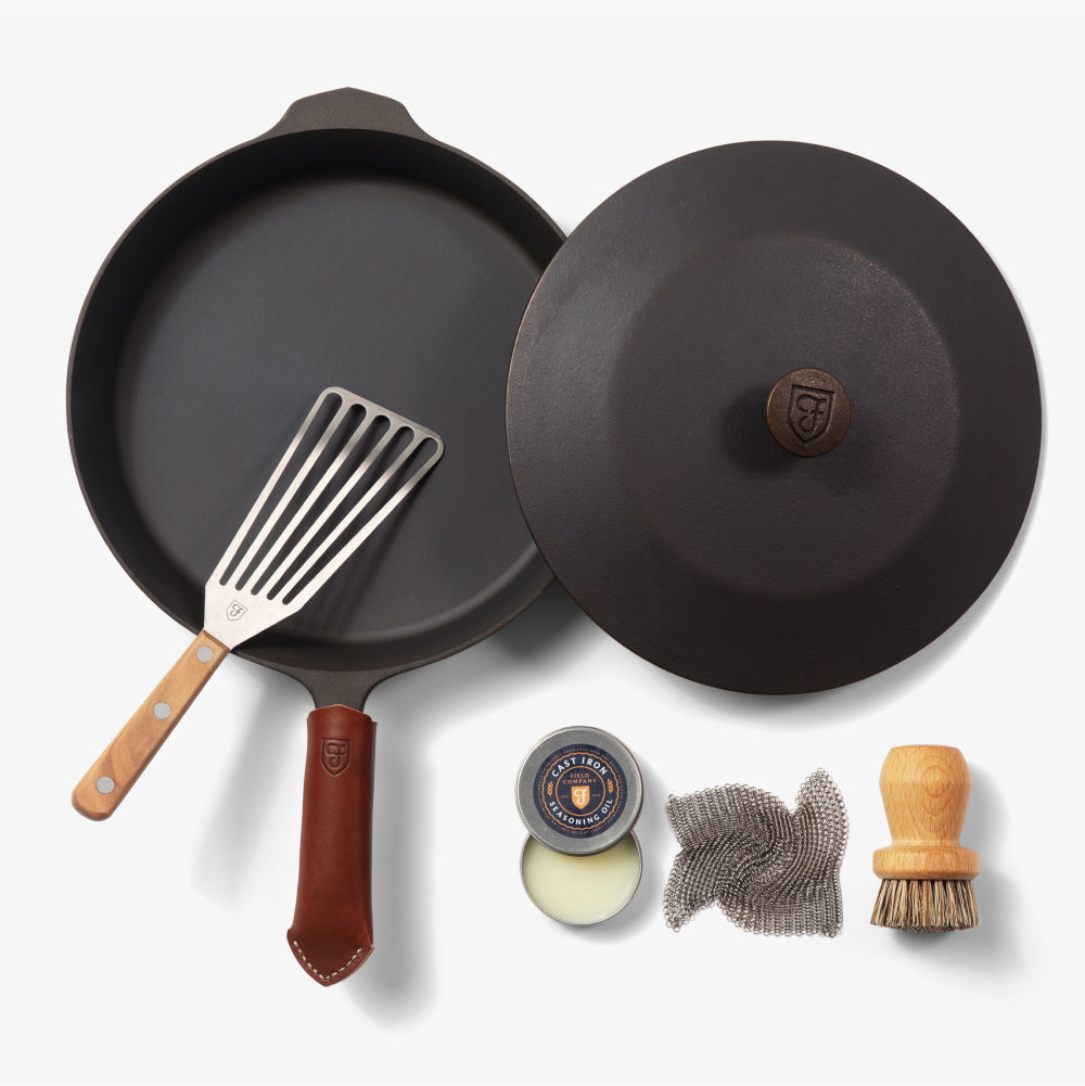 Overhead of the Chef's Starter Set No.10: Field Skillet with lid, slotted turner, leather handle cover, and care tools