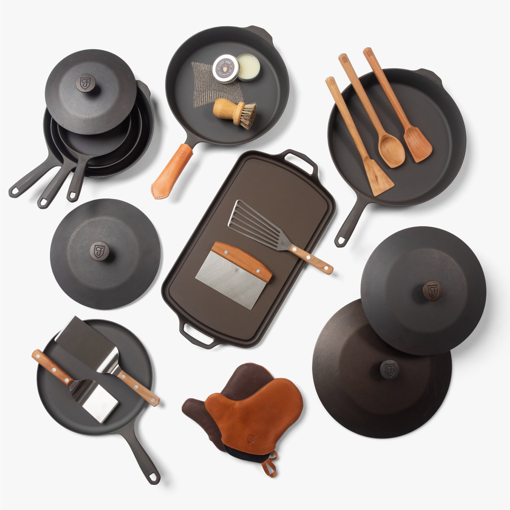 Overhead view of the Cast Iron Collector's Set: Field skillets, Dutch ovens, griddles, lids, wood tools, and oven mitts