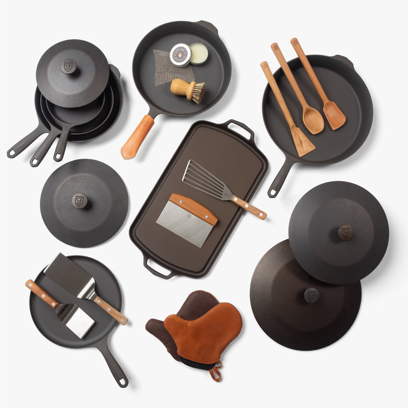 Overhead view of the Cast Iron Collector's Set: Field skillets, Dutch ovens, griddles, lids, wood tools, and oven mitts