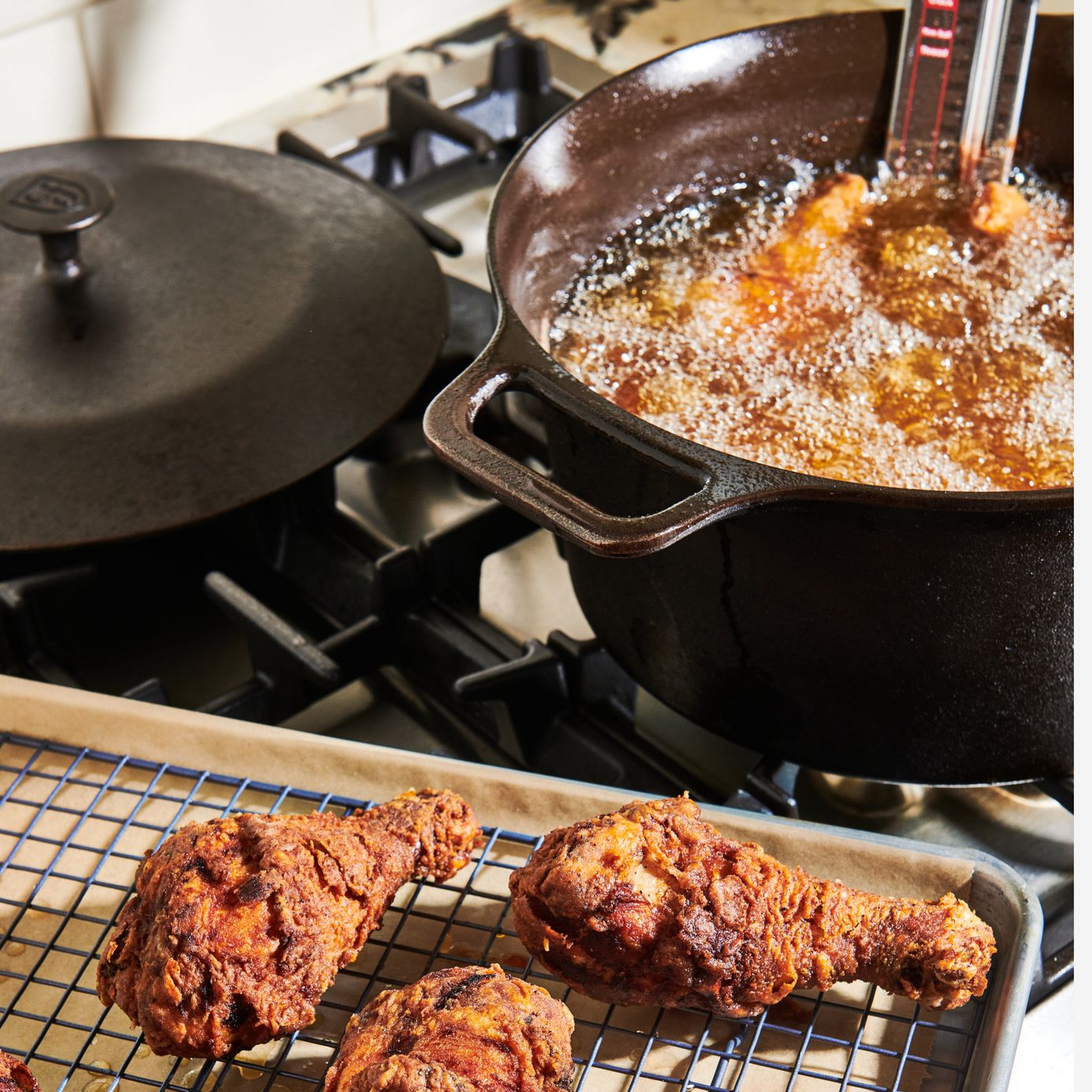 Frying chicken in the No.10 Field Cast Iron Dutch Oven on the stovetop, finished pieces resting on a rack