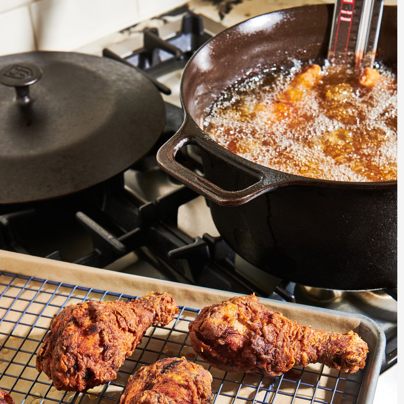 Frying chicken in the No.10 Field Cast Iron Dutch Oven on the stovetop, finished pieces resting on a rack