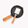 Overhead view of The Minis: small Field Skillet with leather handle cover and Mini Turner resting inside thumbnail