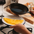 Person slides a folded omelette from the No.5 Field Chef Skillet onto a plate at the stovetop thumbnail