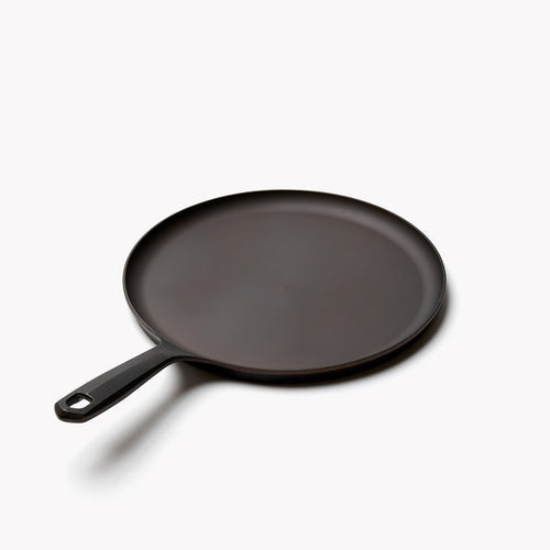 Angled view of the No.9 Field round griddle, low rim and long handle with hanging hole