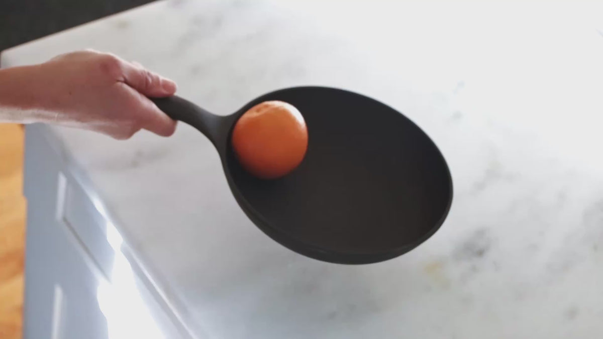 Video of a hand holding a Field Skillet with an orange resting inside on a marble counter