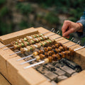 Hand turning yakitori skewers over charcoal on a brick DIY Konro grill from Field Company thumbnail