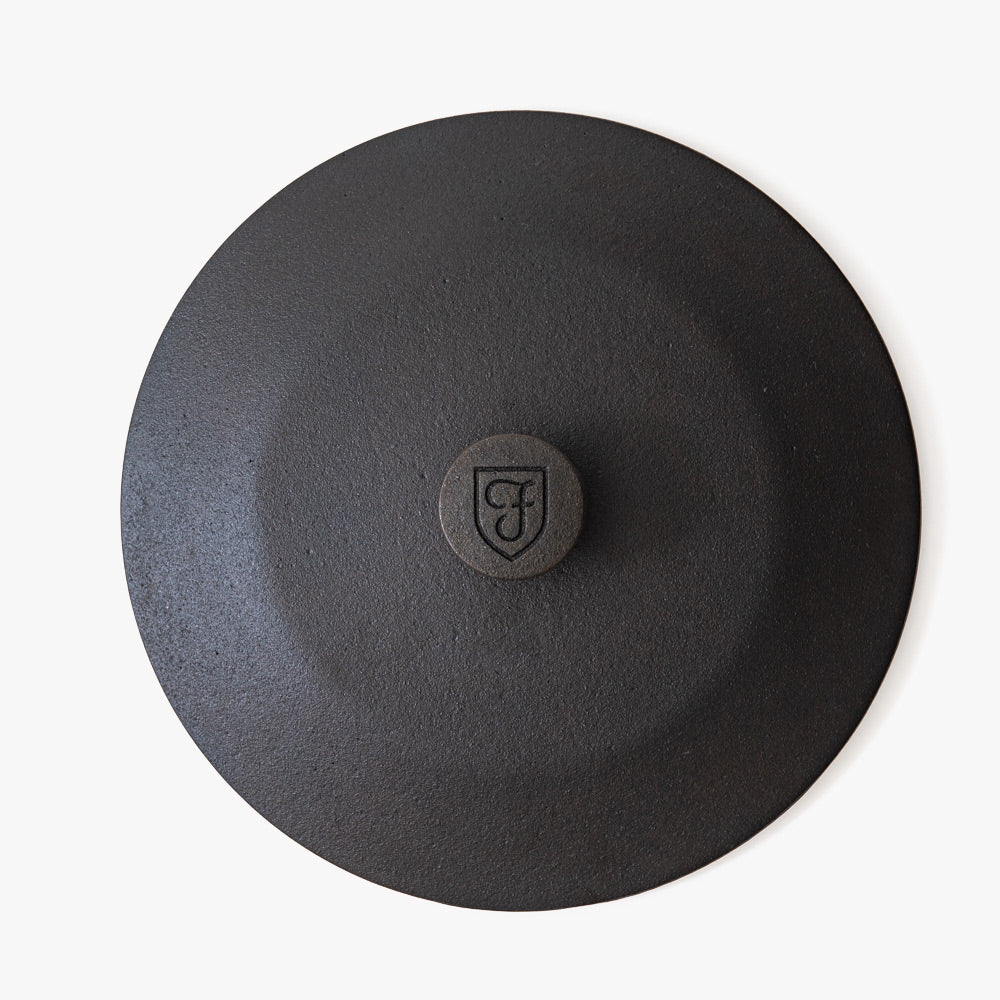 Top-down detail of the Field cast iron lid with shield-stamped knob at center
