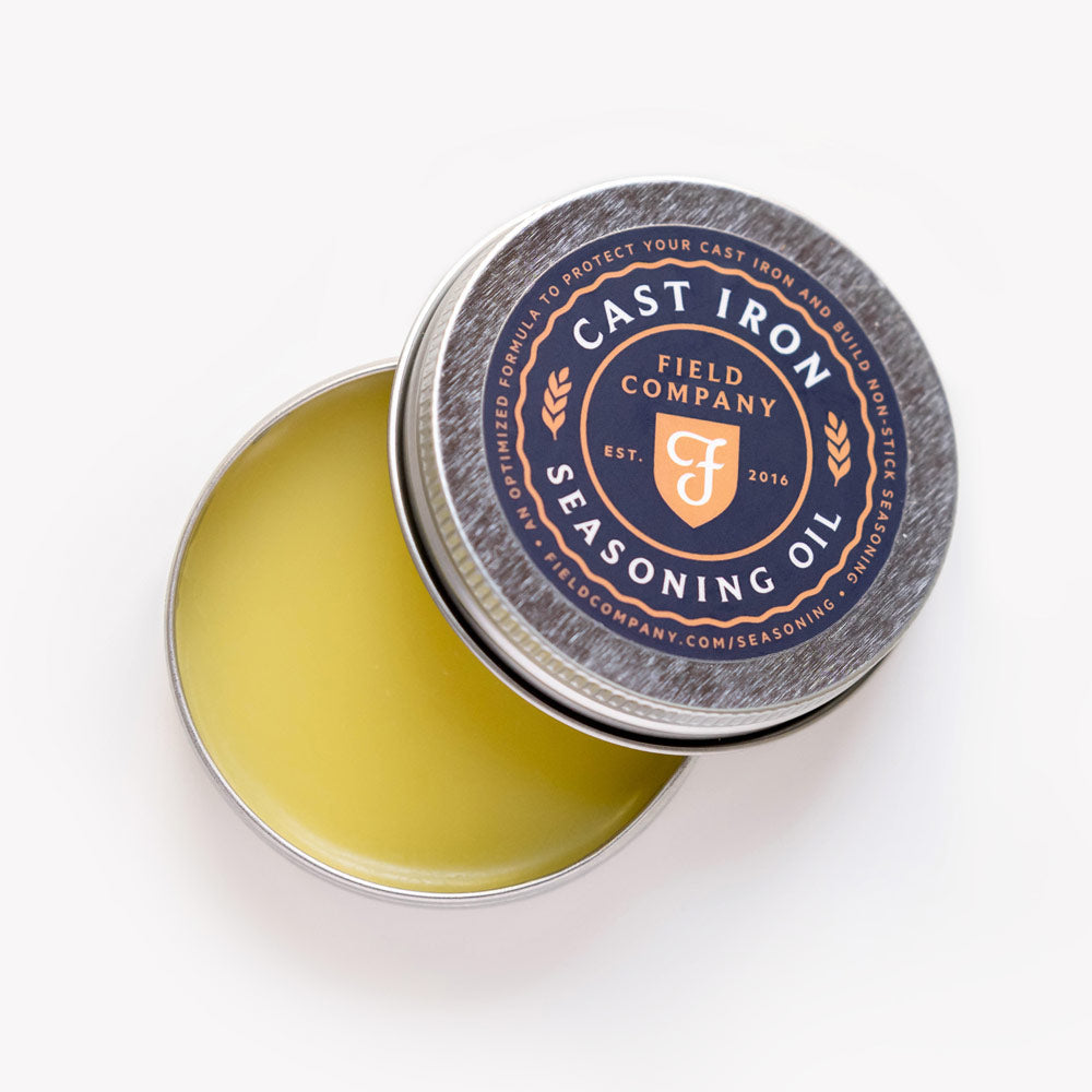 Open tin of Field Company Cast Iron Seasoning Oil with the lid tilted to show the balm-like oil blend inside