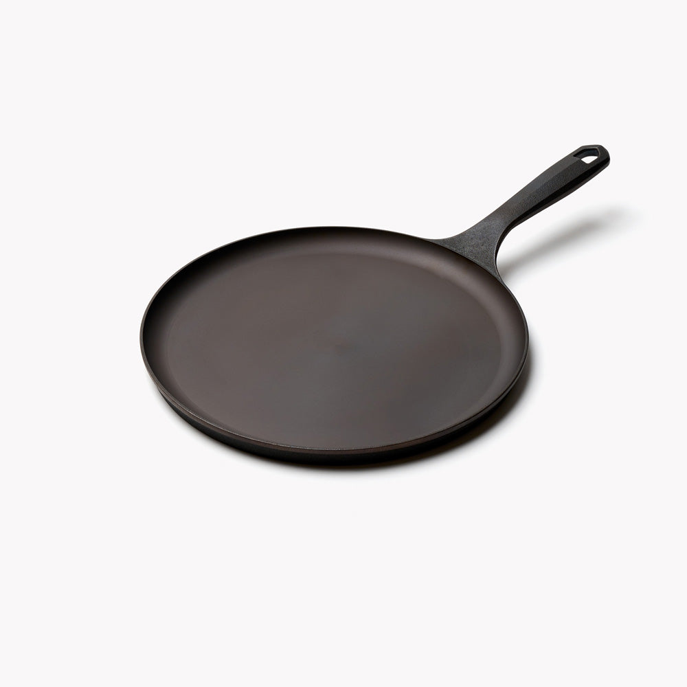 Angled view of the No.9 Field Round Cast Iron Griddle with a low rim and long handle with hanging hole