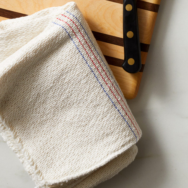 Field Company XL Cleaning Cloth with red and blue stripes folded on a cutting board beside a knife